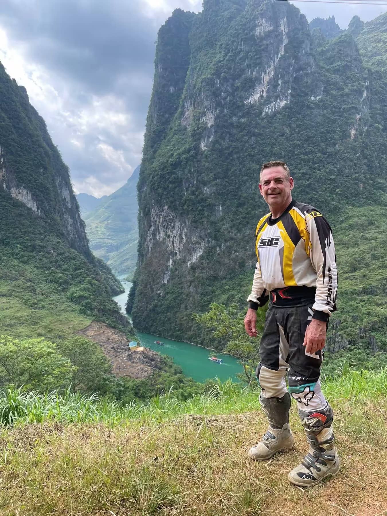 A smiling guest rider standing on the edge of the Ma Pi Leng canyon above the river