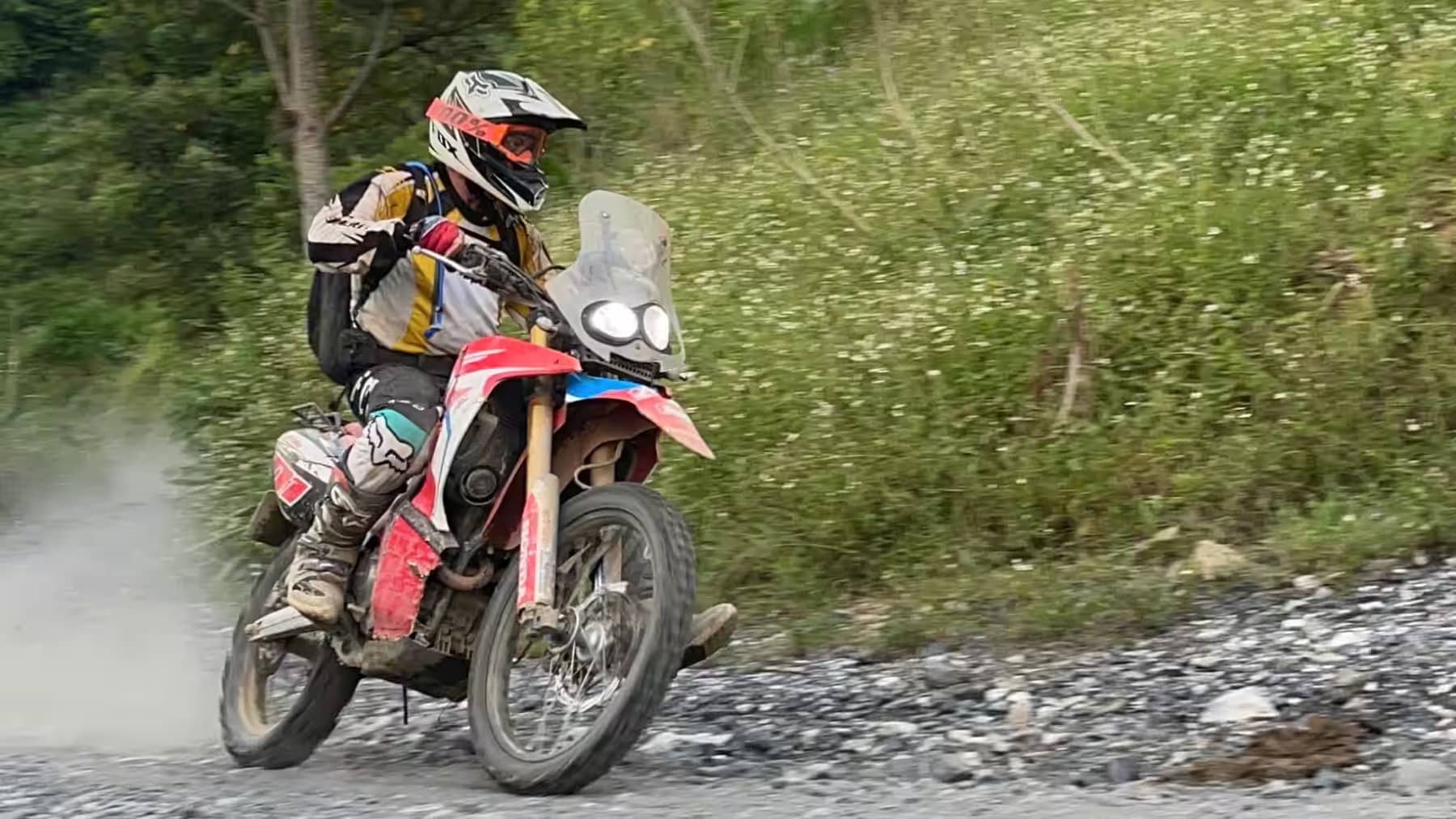 A guest kicking up dust on a gravel corner on a Ha Giang dirt bike trail
