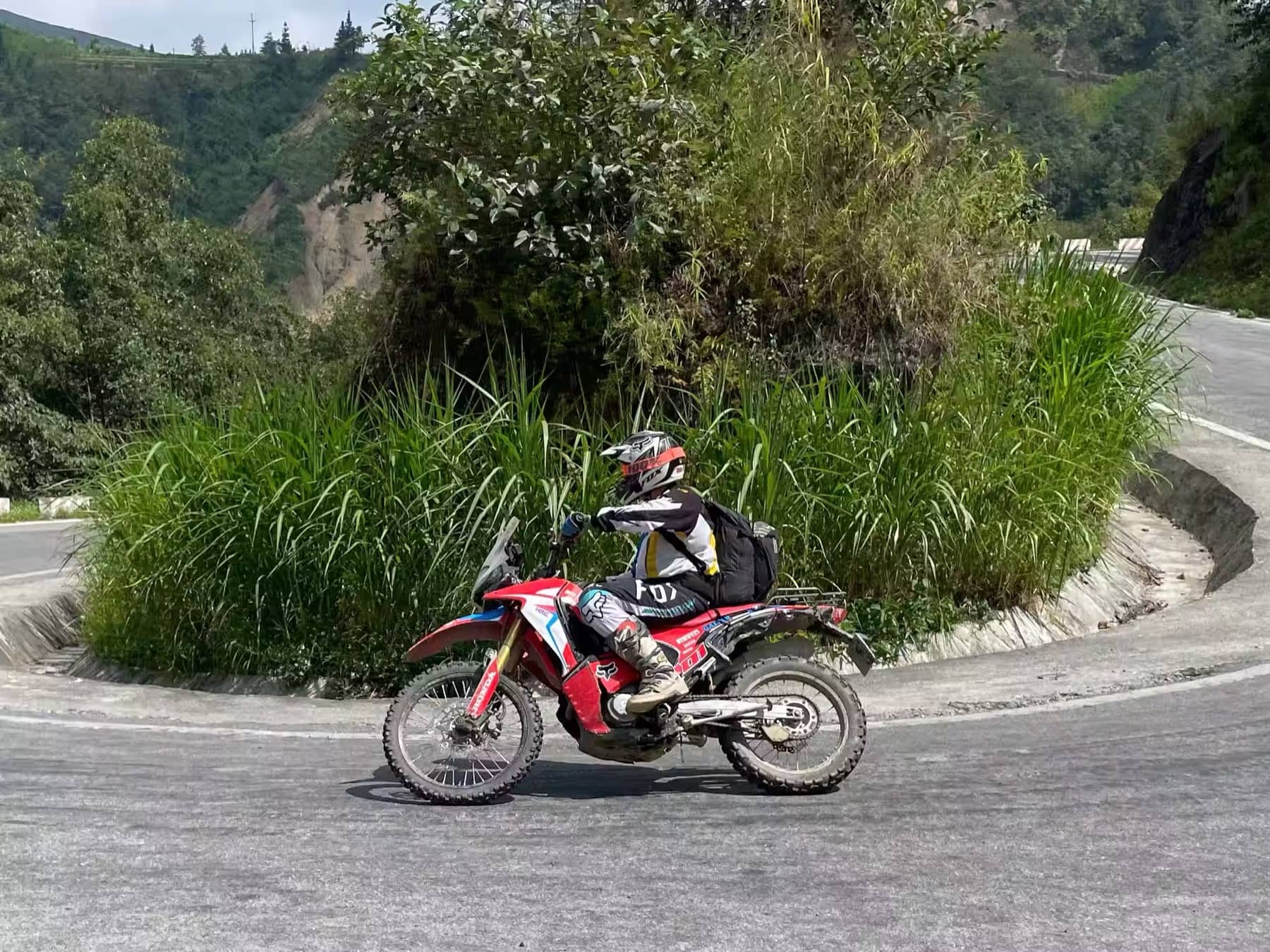 A guest leaning a dirt bike through a tight hairpin bend on a Ha Giang mountain road