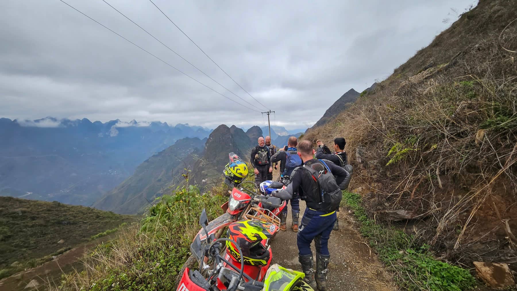 A group of guests riding dirt bikes up a winding mountain pass on the Ha Giang Loop in northern Vietnam