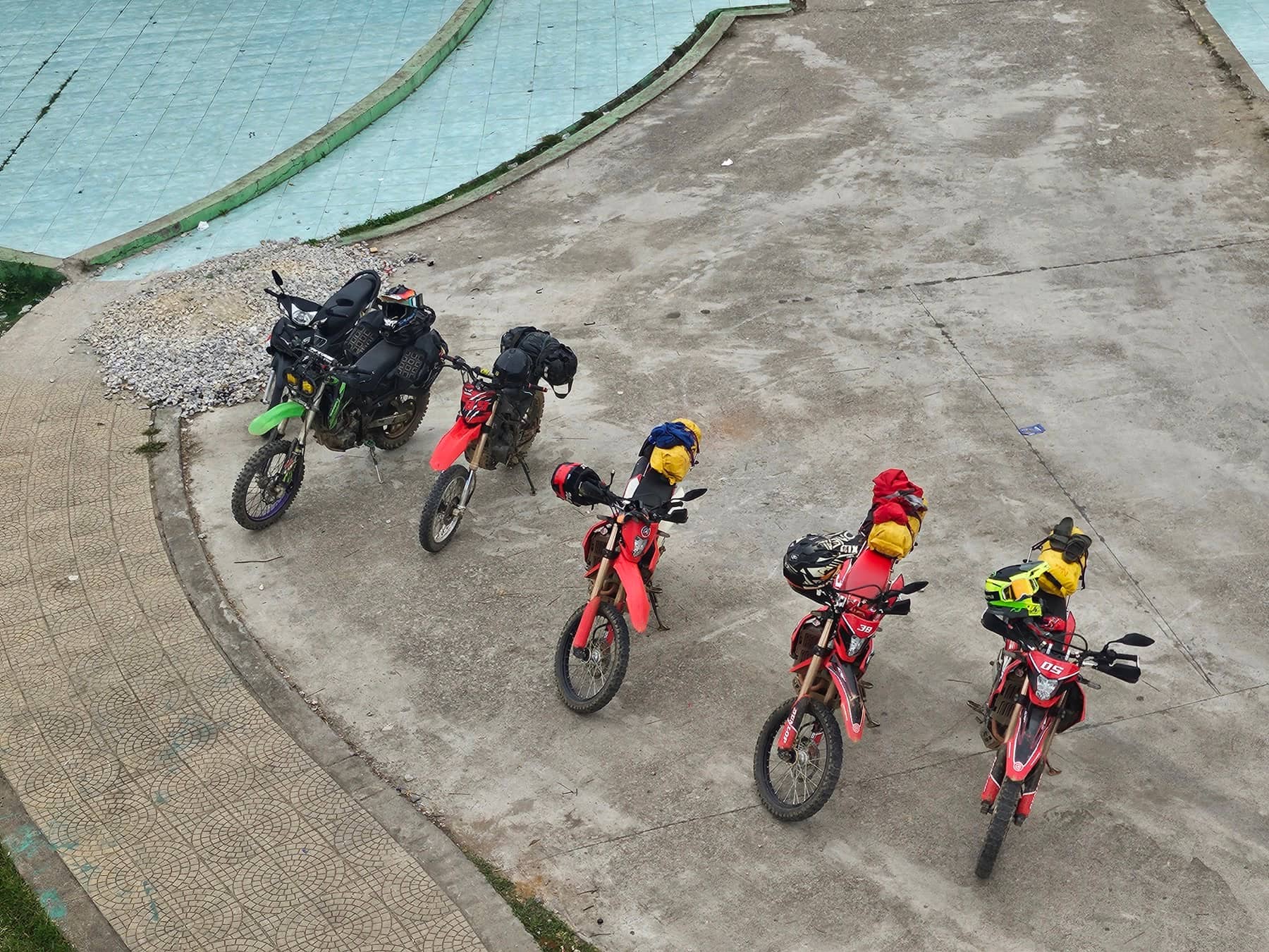 A group of dirt bikes and their riders lined up and ready at the start of a Ha Giang trail