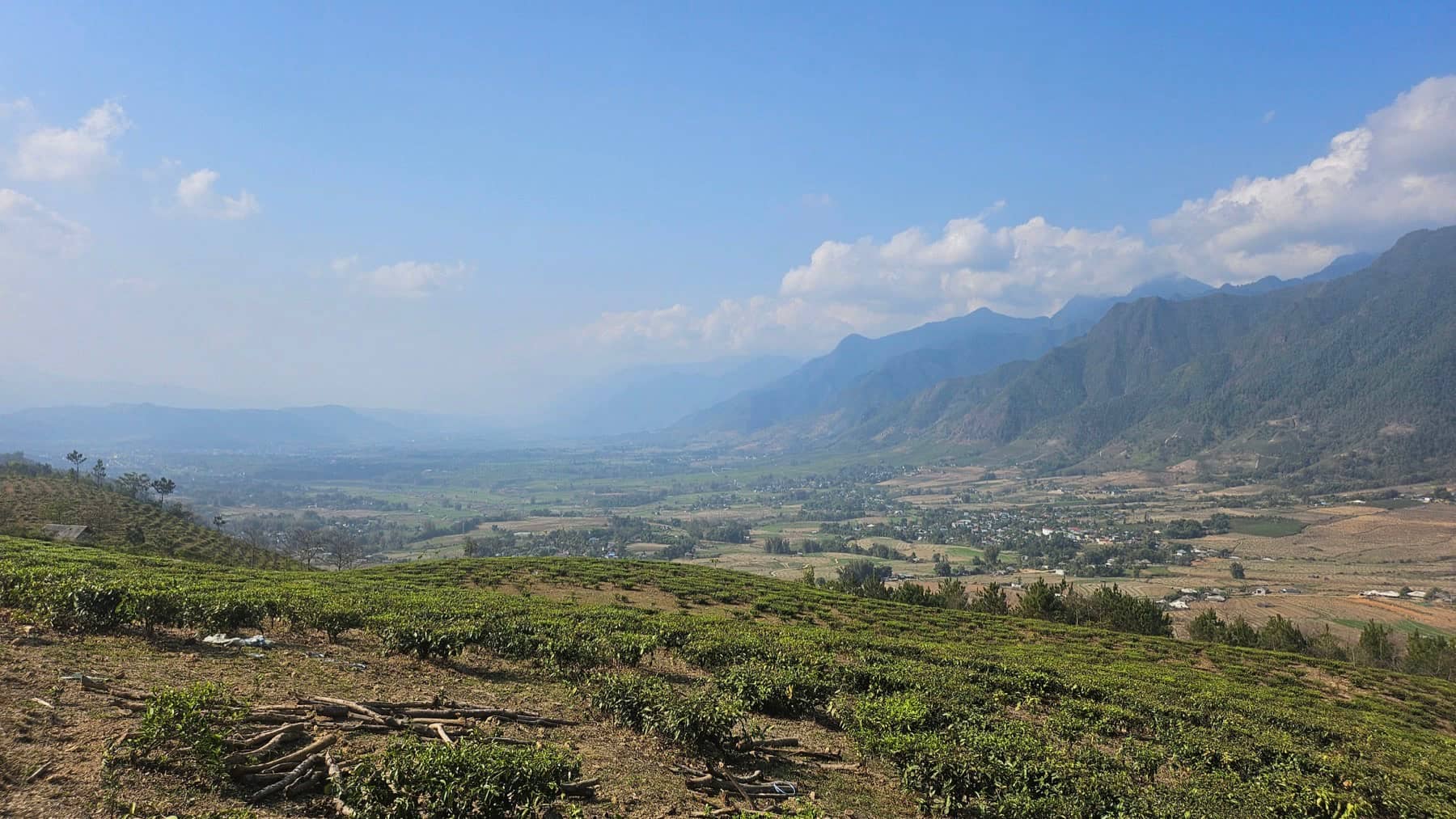 A wide panorama across a green Ha Giang valley seen from the loop road