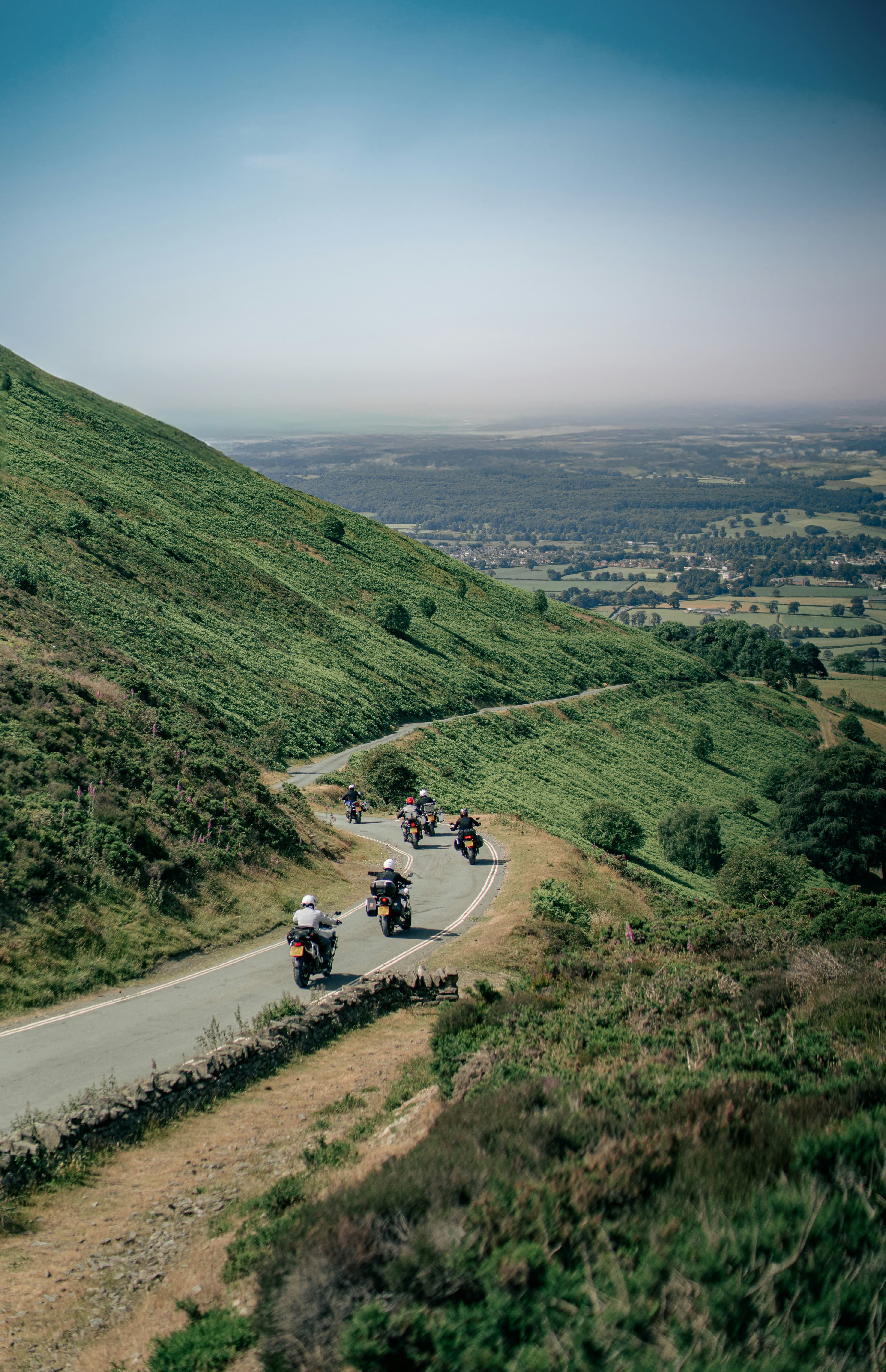 Touring bikes on a road winding down a green hillside