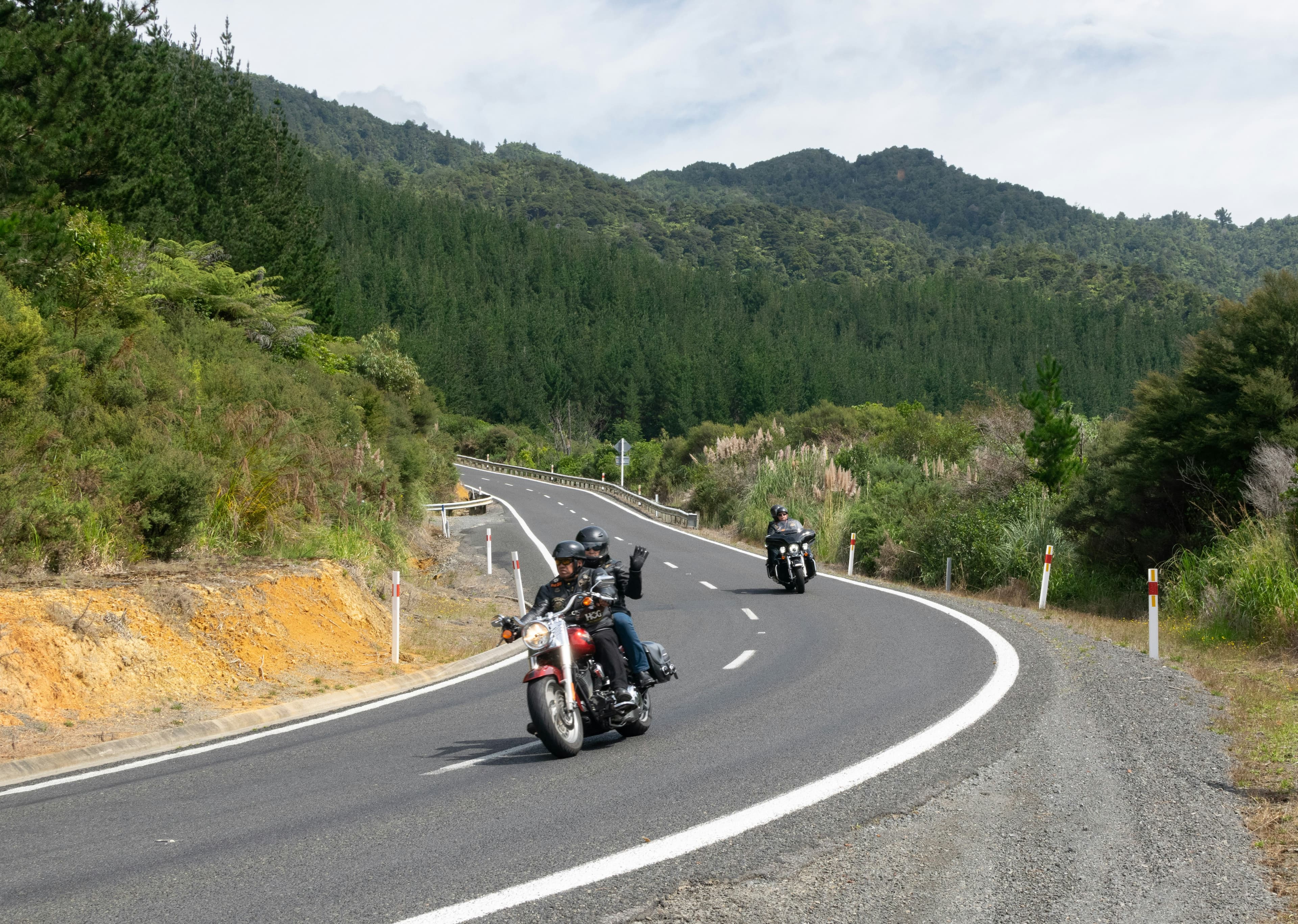 A group of riders on a winding road through green hills