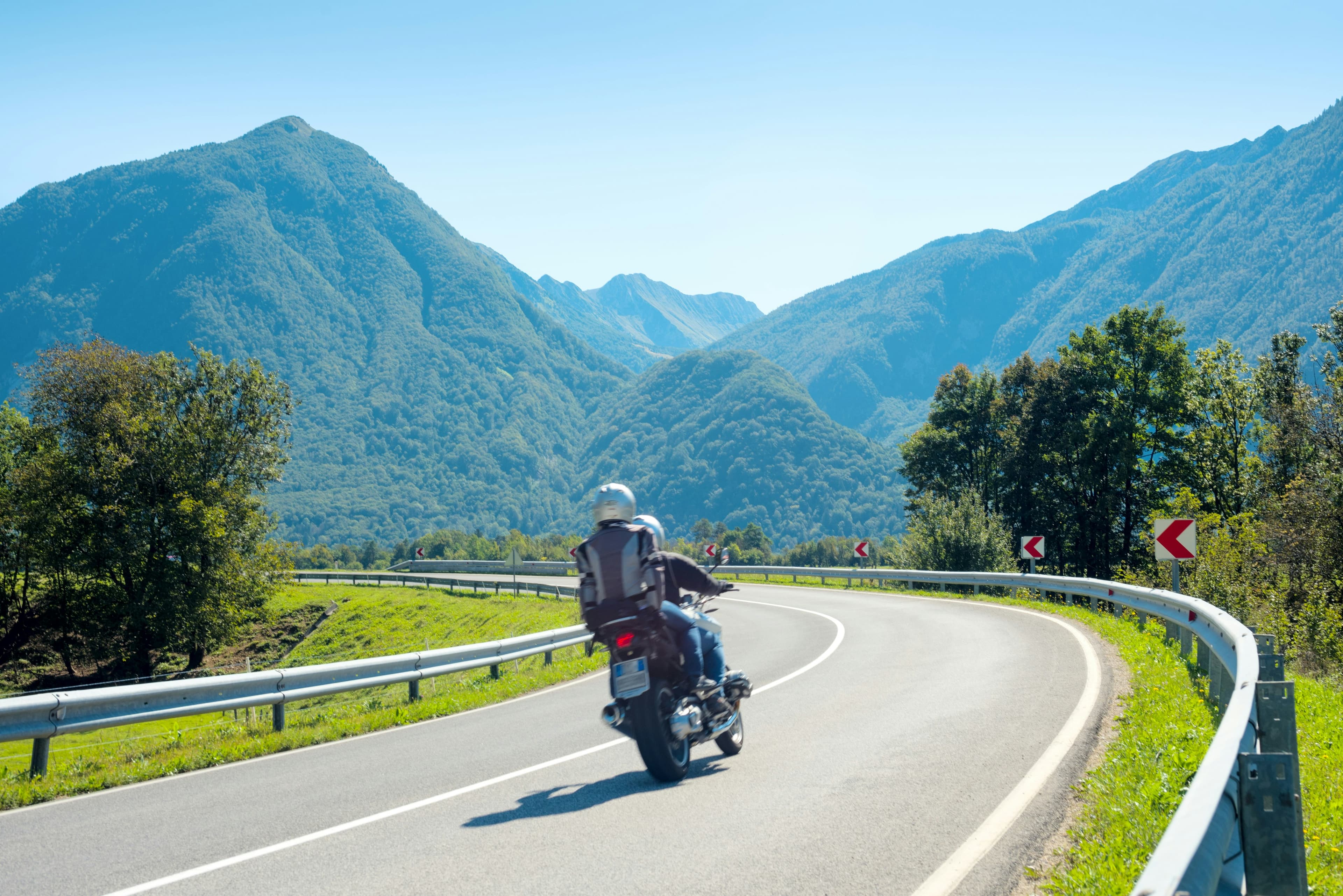 Motorcycle on a sweeping road heading into green mountains